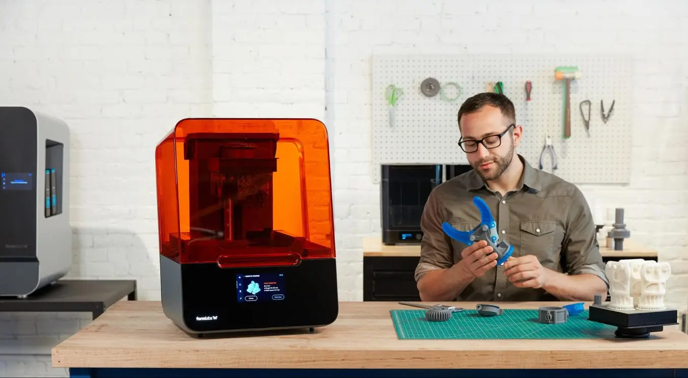 Die orangefarbene Acryl-Abdeckung der Stereolithografie-3D-Drucker von Formlabs ist unverzichtbar, da sie zur Markengeschichte gehört und zudem UV-Licht blockiert, das die Vorgänge im Drucker sonst stören würde.