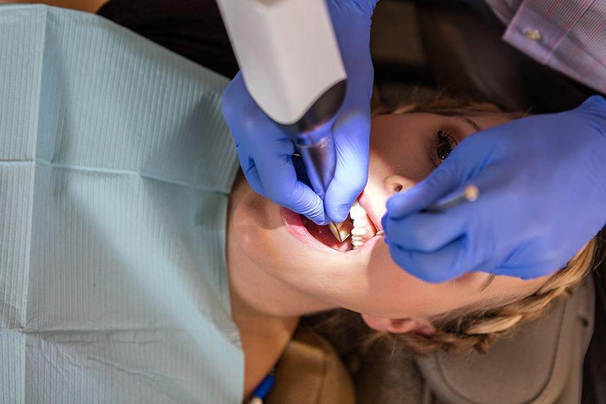Dental professional wearing blue gloves taking an intraoral scan of a patient