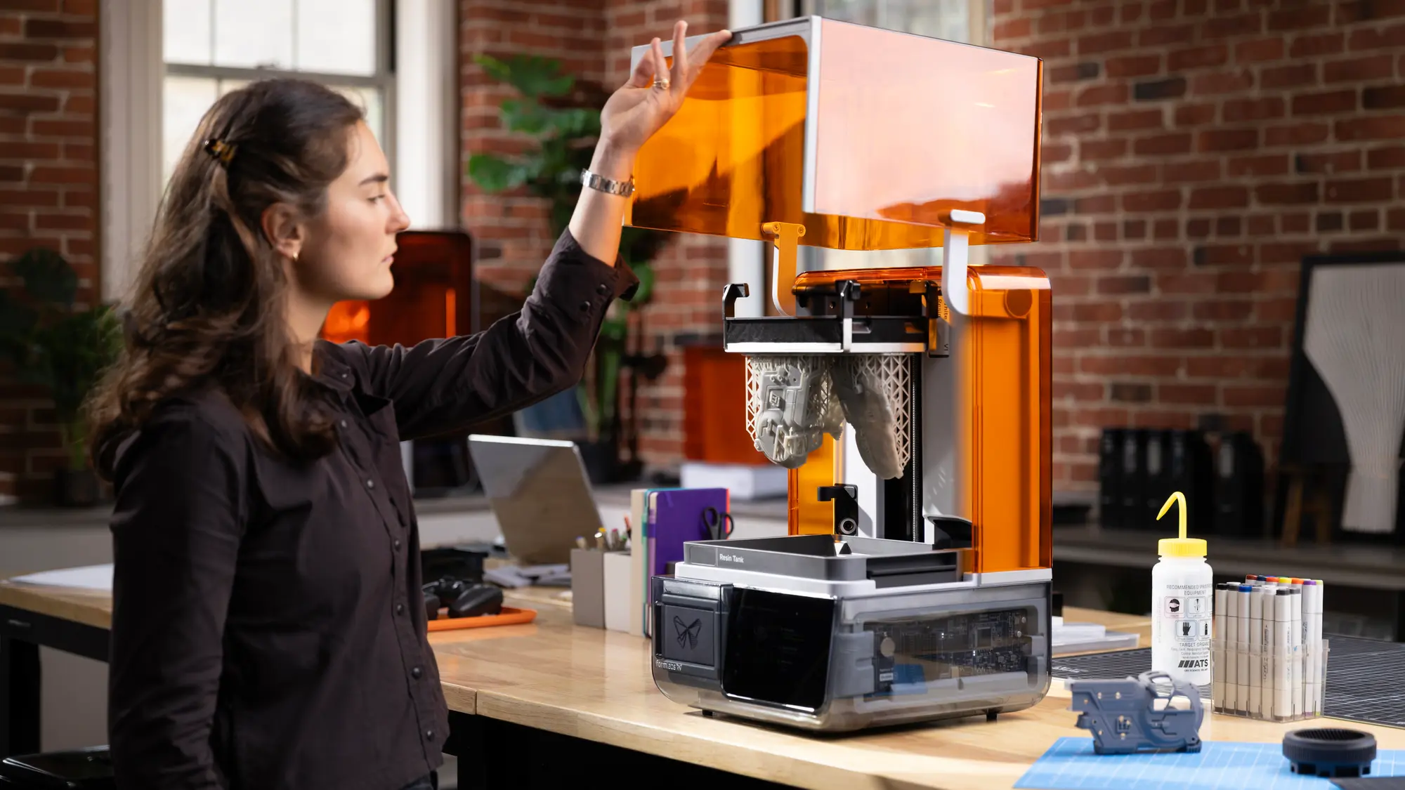 A person opening a Form Studio 1 resin 3D printer.