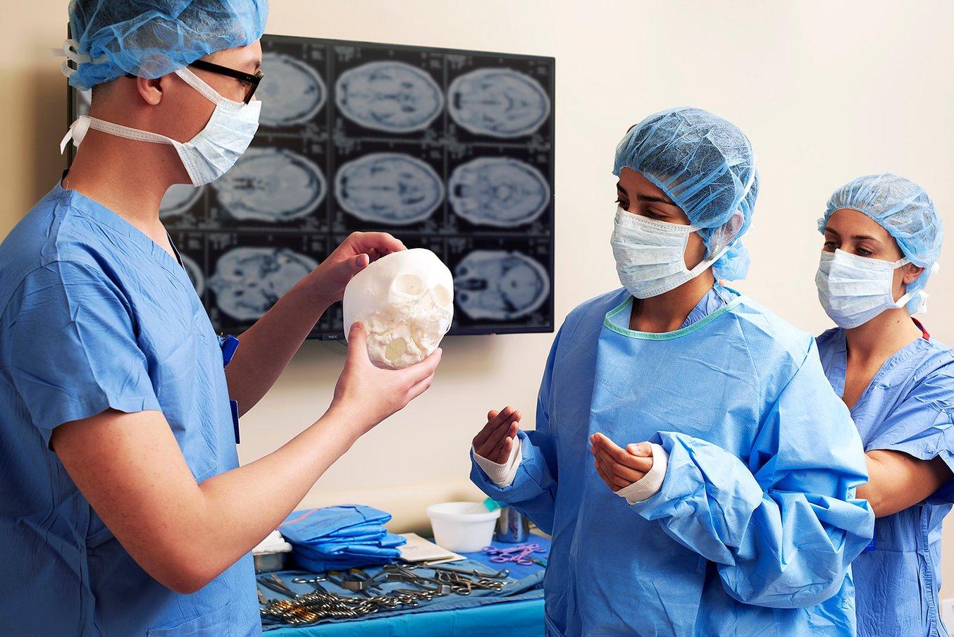 Two people in PPE holding a 3D printed skull