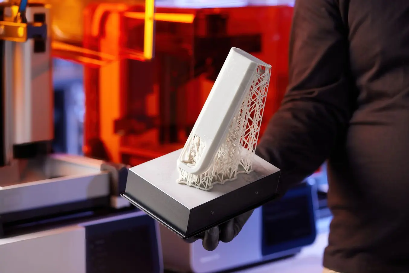 Una persona mantiene una piattaforma di stampa con una torre realizzata in 3D