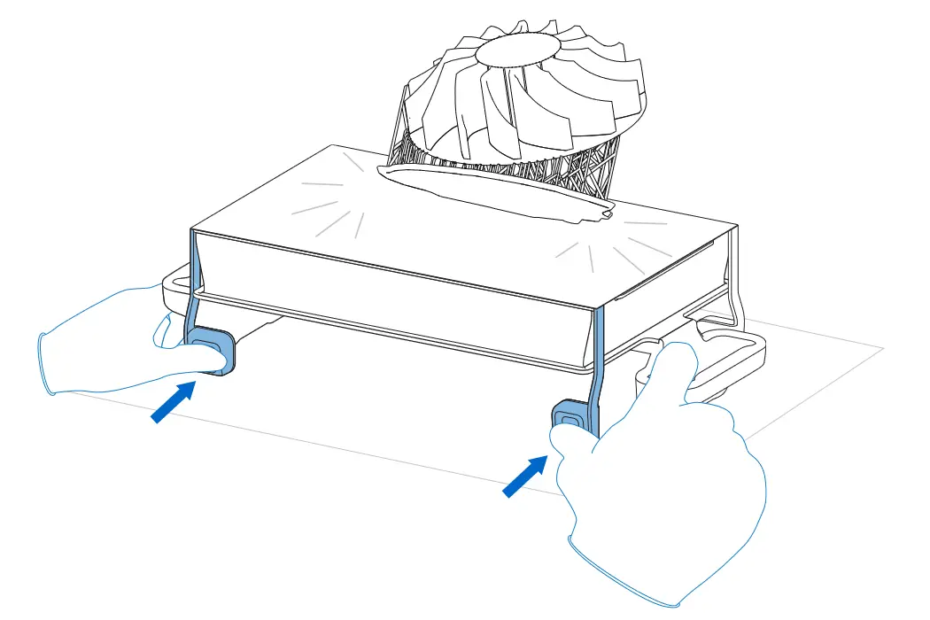 The Build Platform 2L is place flat on the work surface. Two hands push both part release tabs inwards to release the large part.