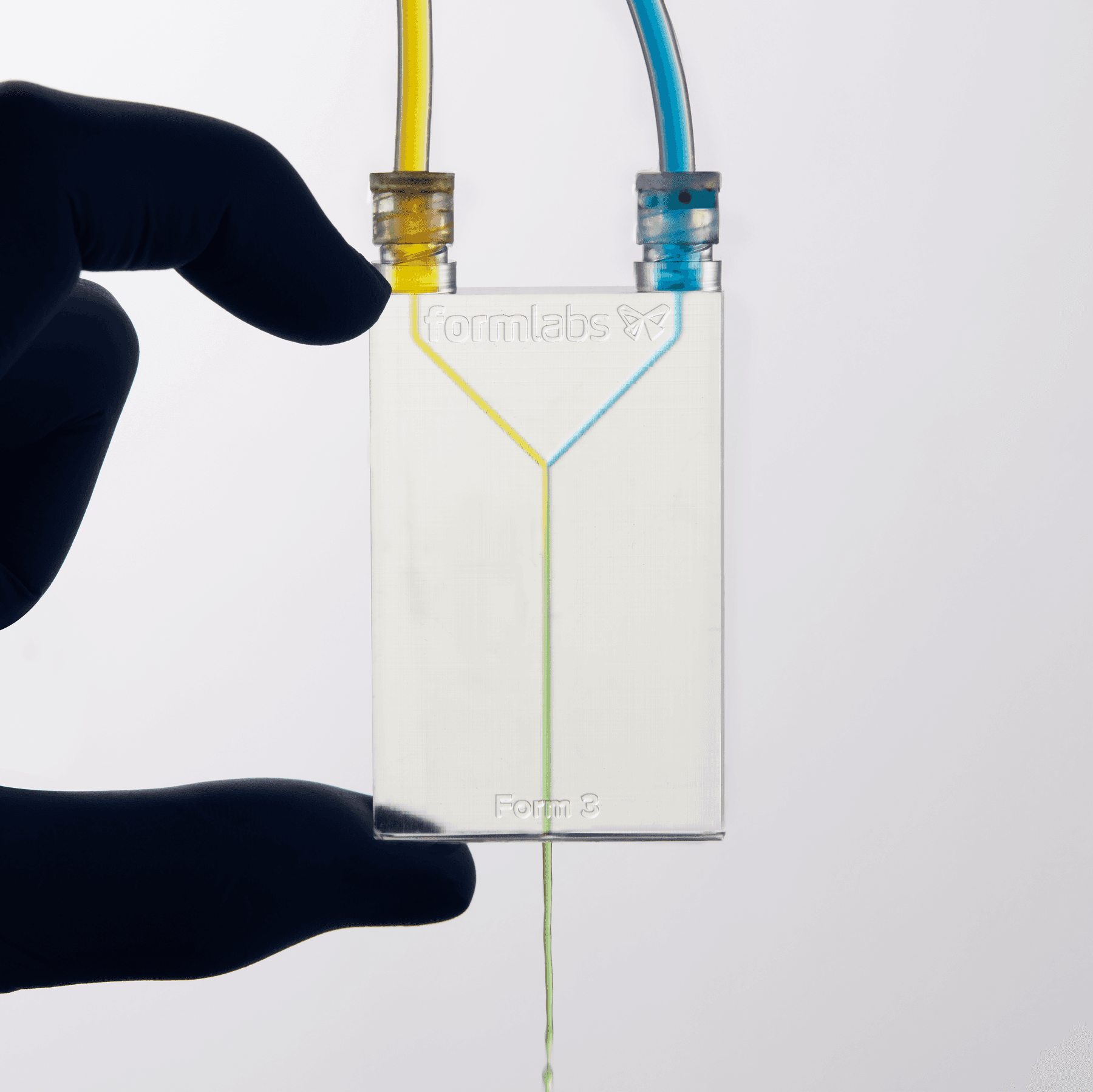 A clear fluidic device with 1.1 mm channels. Yellow liquid enters from top left and blue from top right, mixing to form green