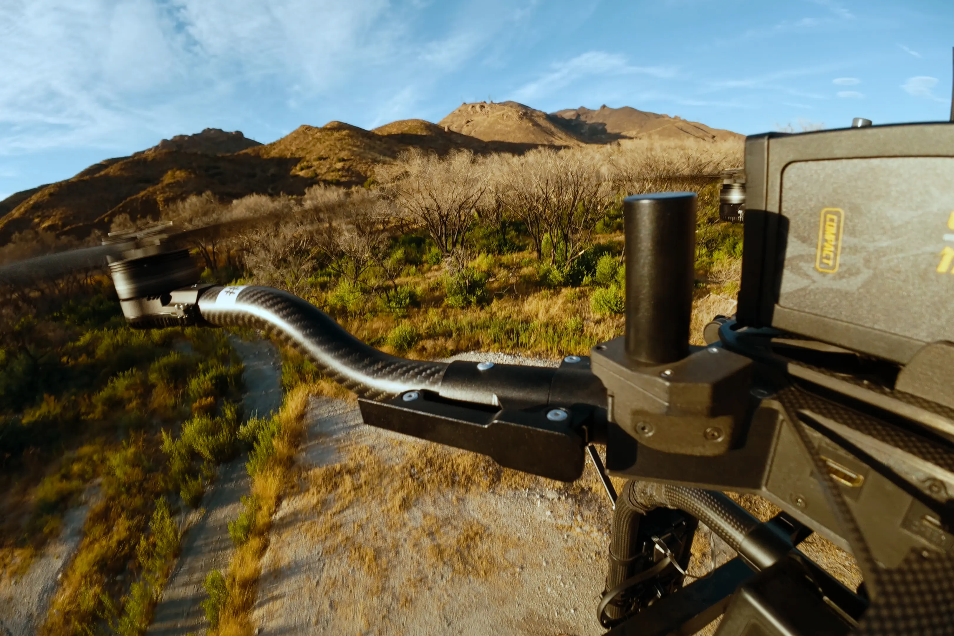 A custom-built, black 3D-printed drone set against an outdoor mountain landscape.