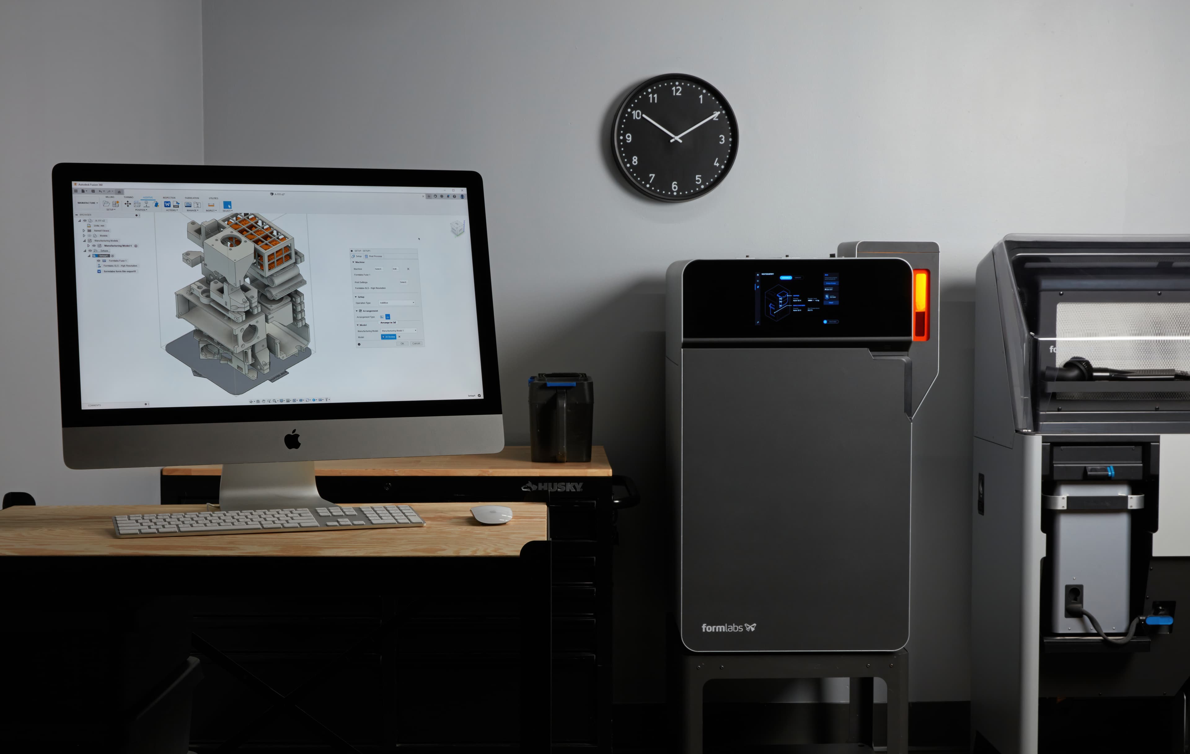 a computer with autodesk fusion on the screen and a Fuse Series sls 3d printer