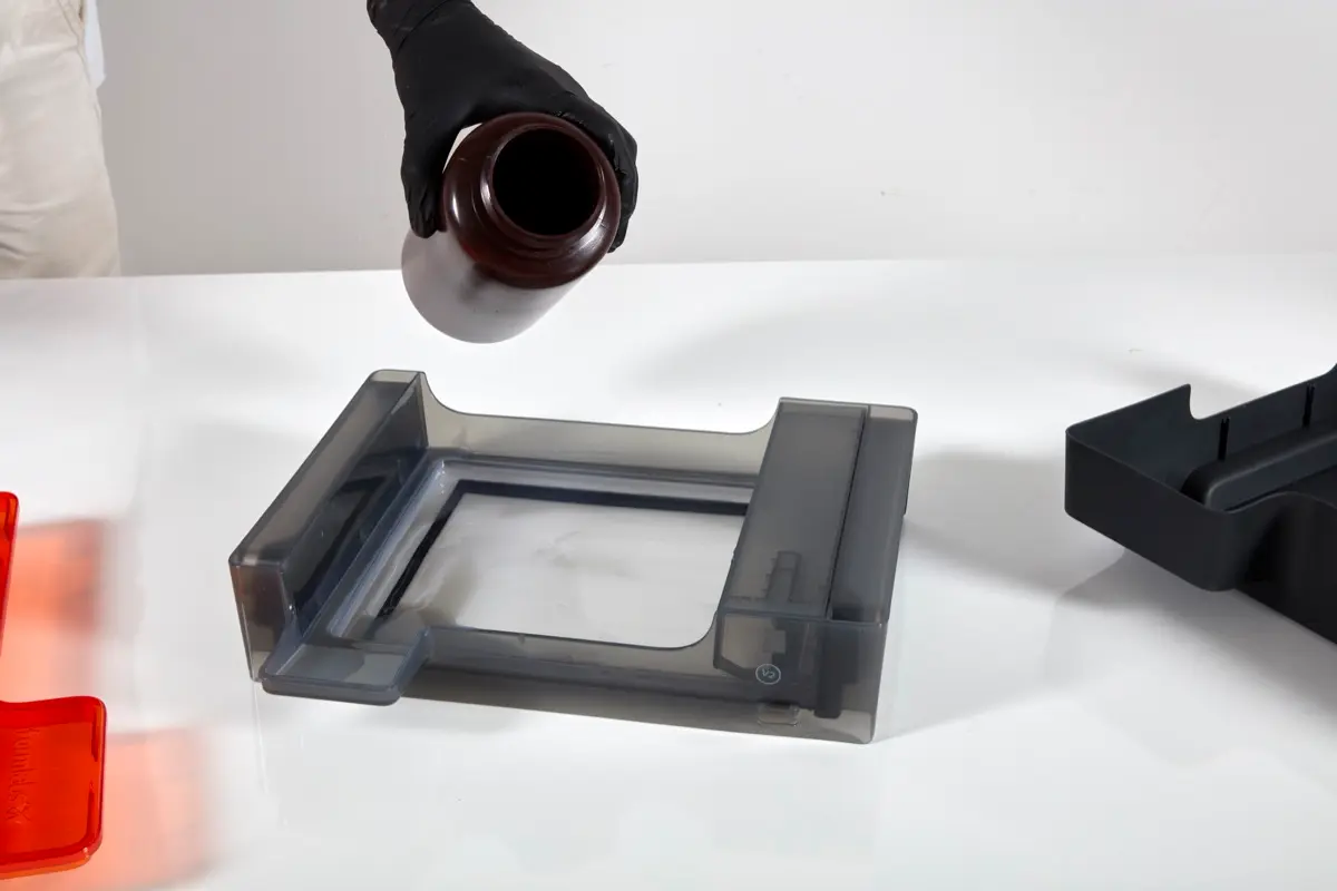 濾過されたレジンを不透明なプラスチックの容器からForm 3のレジンタンクに戻します。