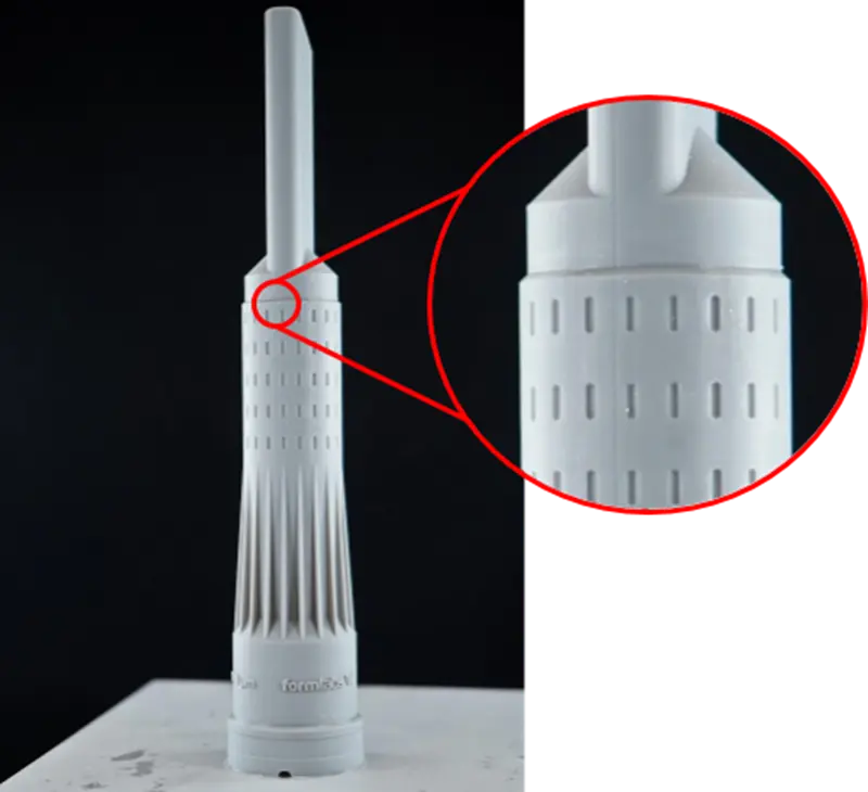 A Formlabs-branded vacuum nozzle is resting in the middle of the build platform after being washed. There is a magnification of the seamline shown.