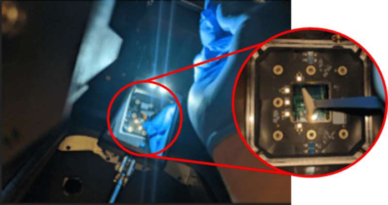 A mirror wand is inserted into the print enclosure as someone brings a swab to the upper laser window