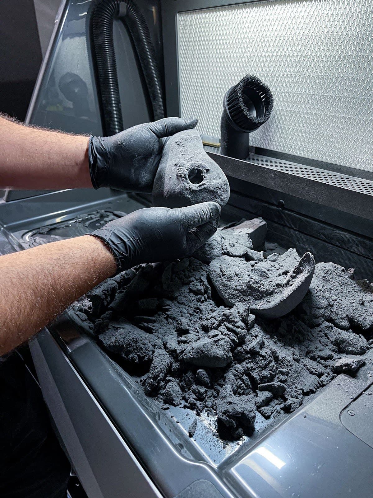 hands removing excess powder from SLS parts in a Fuse SIft
