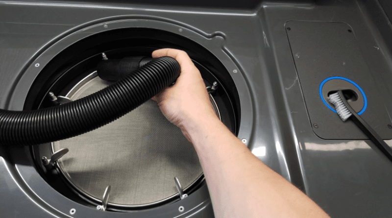 Someone is holding the vacuum hose against the mesh beneath the grate