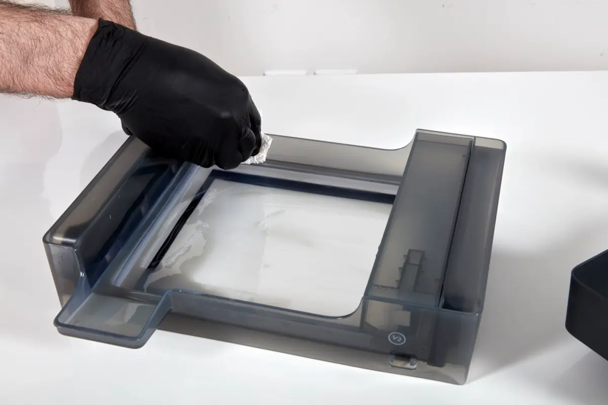 Form 3 resin tank is wiped by a gloved hand and a paper towel.