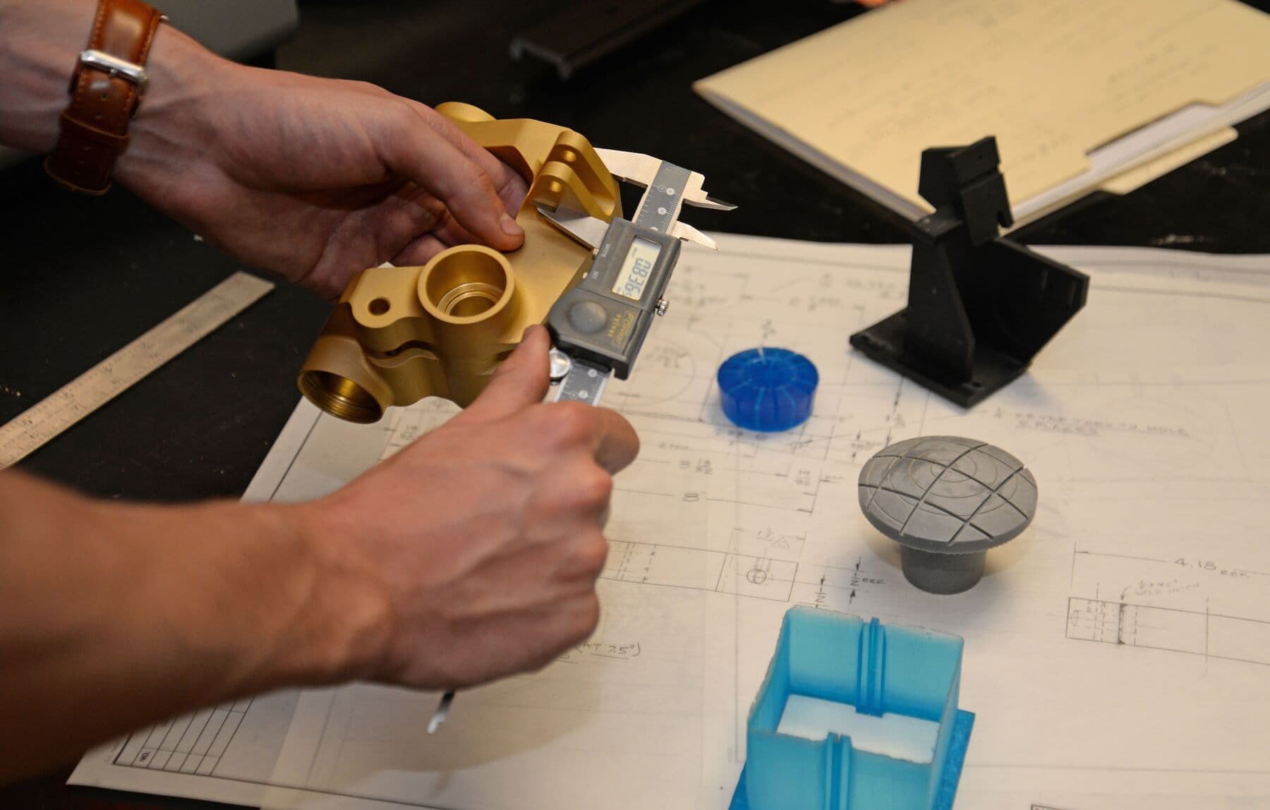 hands hold calipers measuring a metal part