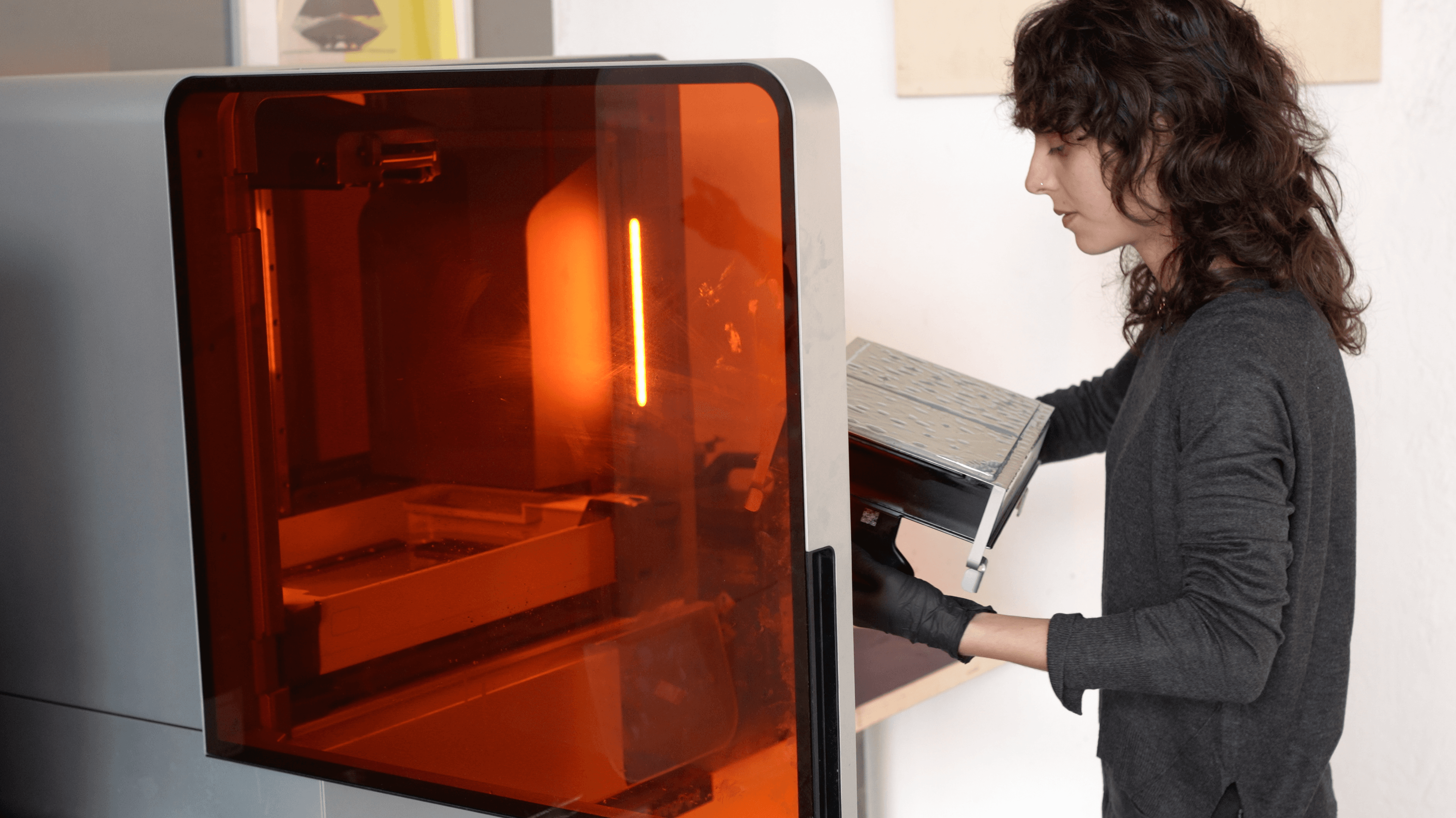 Person wearing gloves inspecting parts on a Form 4L Flex Build Platform.