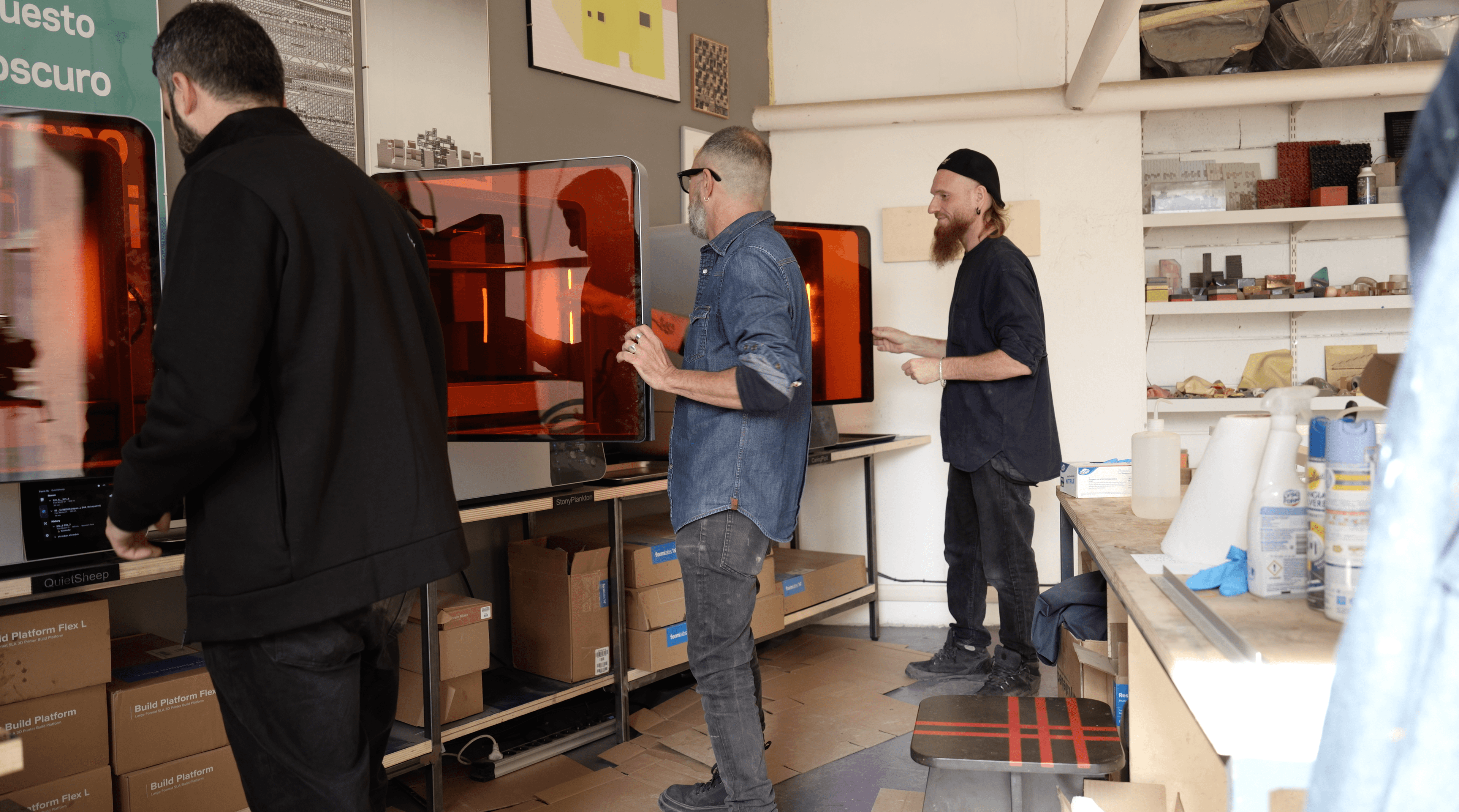 Three people each opening a Form 4L 3D printer inside a studio.