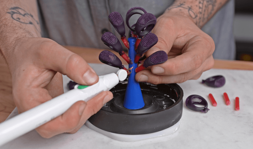 Person using a heat pen to join resin patterns to the wax sprue tree
