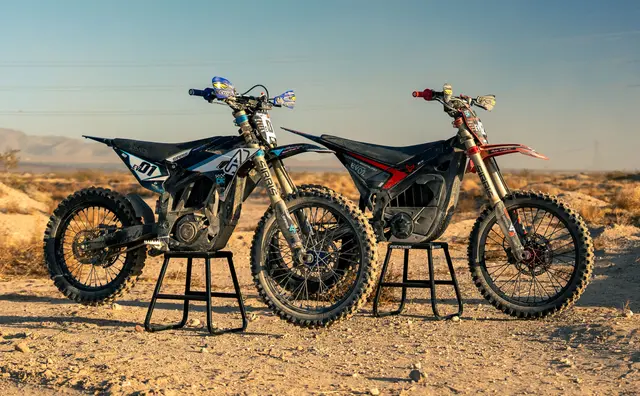 Two dirty electric dirt bikes in the desert