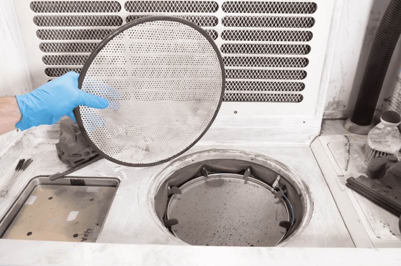 A gloved hand is holding the sifter mesh