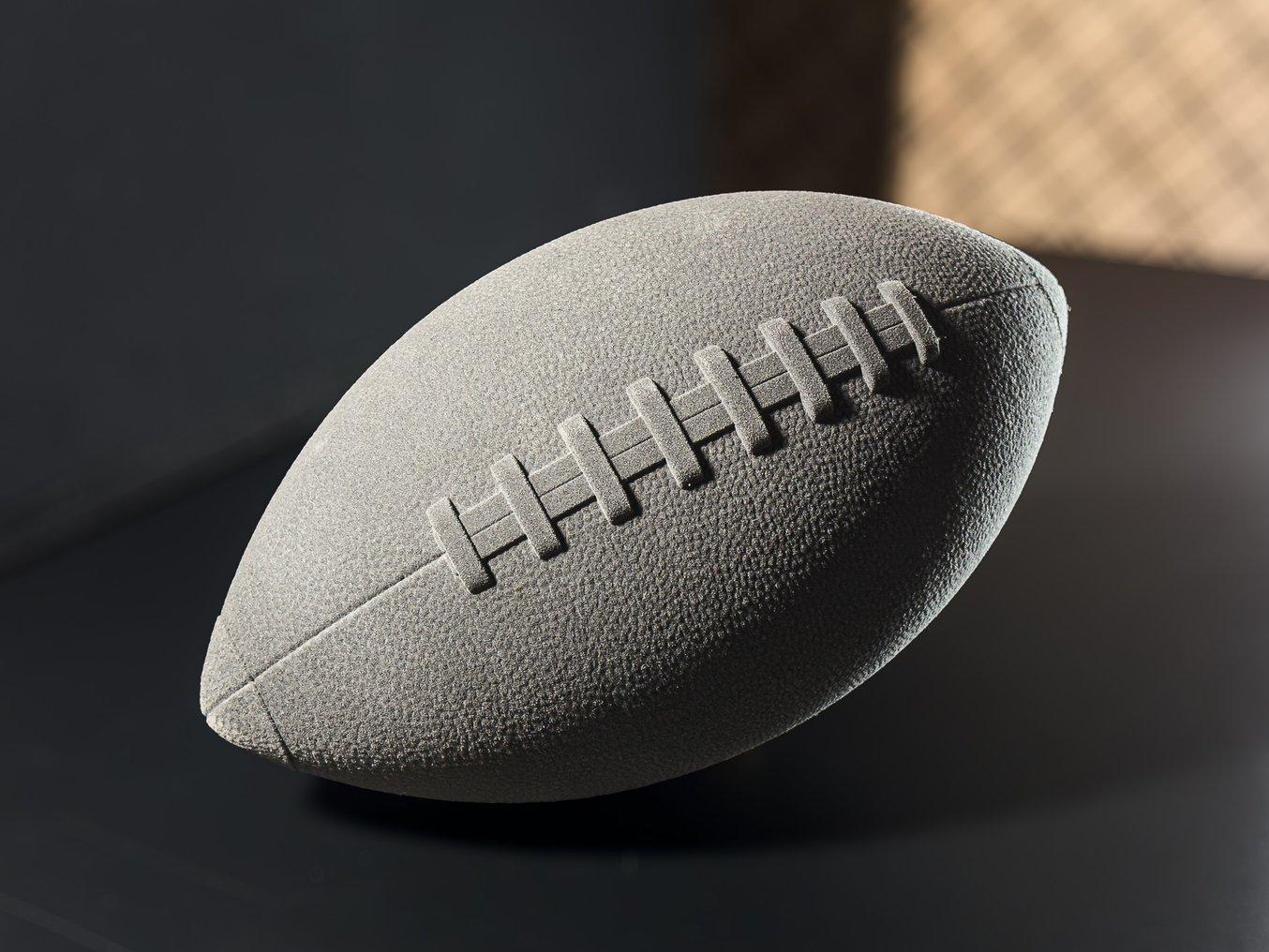 Dark grey 3D printed football on black background