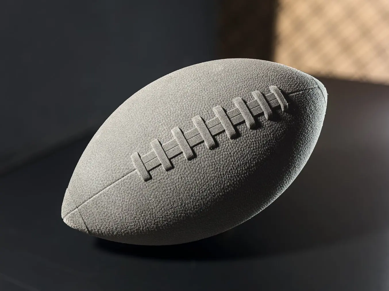 Dark grey 3D printed football on black background