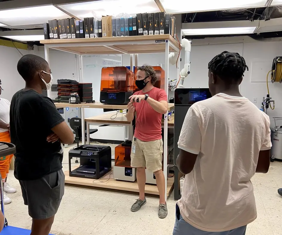 Formel hosting a group of students visiting the lab, with several 3D printing technologies represented, including Formlabs SLA and SLS printers.