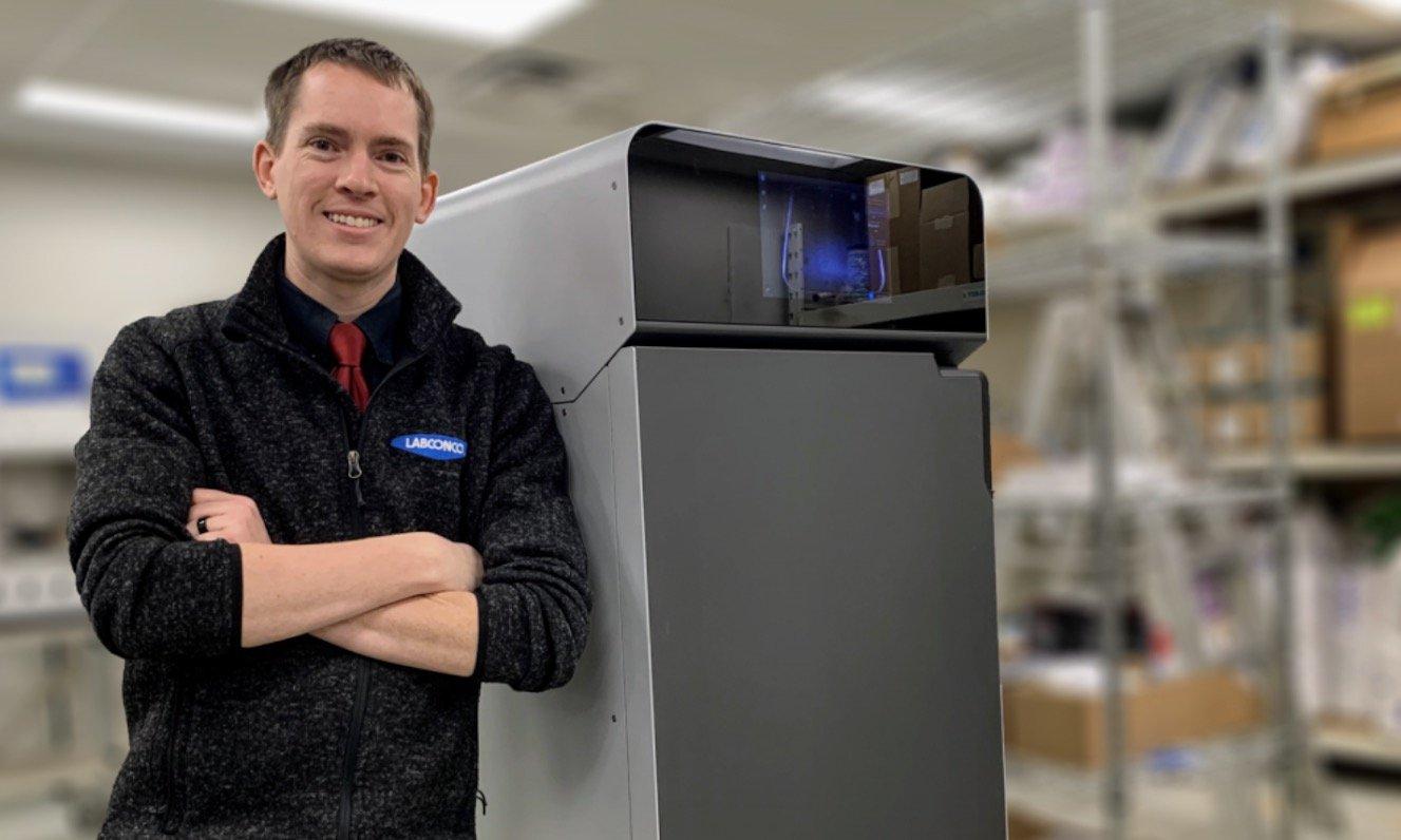a man stands in front of an SLS 3D printer