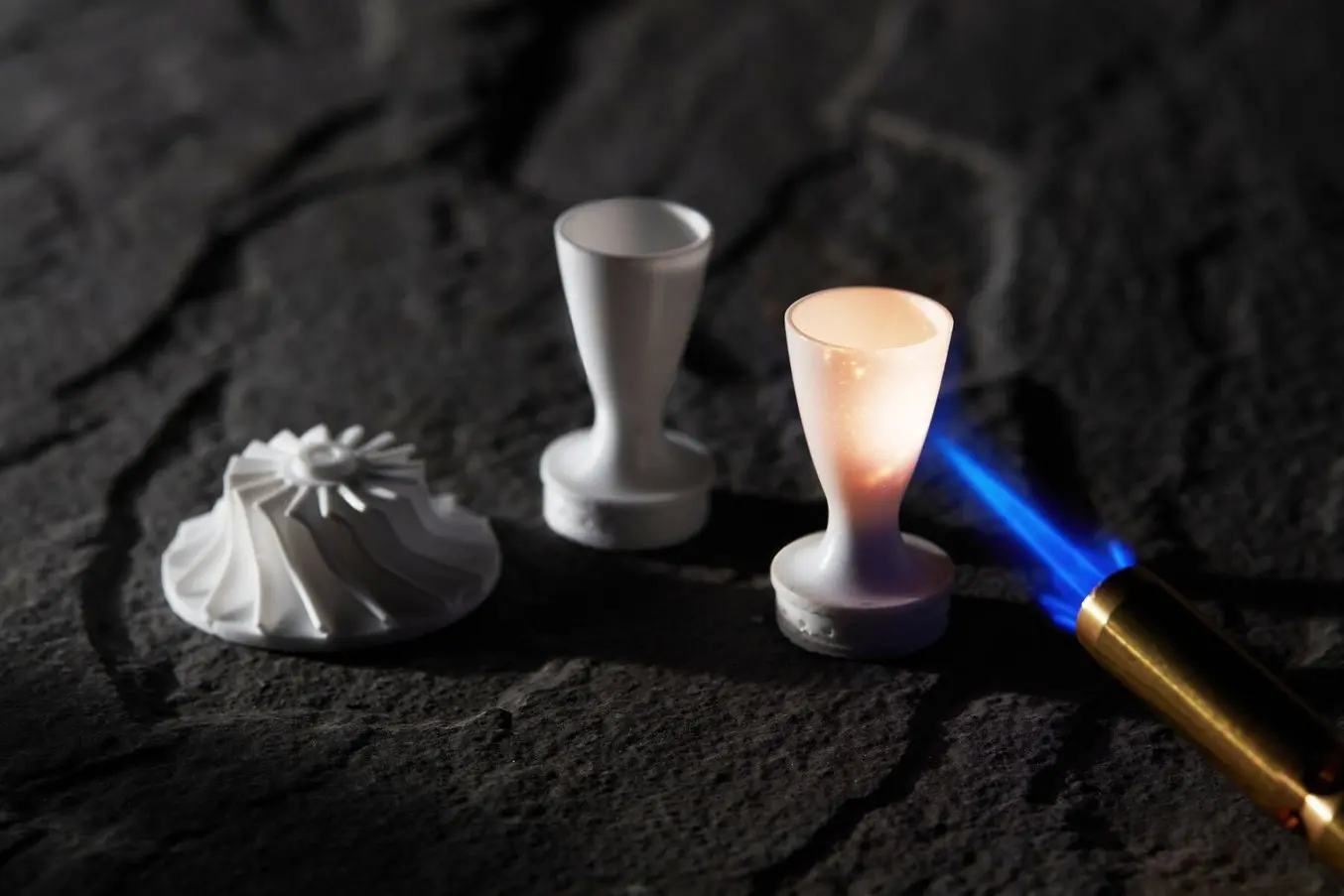 a flame heats up a 3d printed ceramic part printed on the Form 3 in Alumina 4N resin with two other ceramic 3d printed parts in the background
