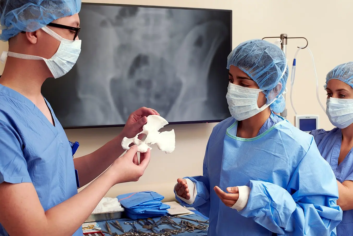Three doctors with a 3D printed pelvis anatomical model