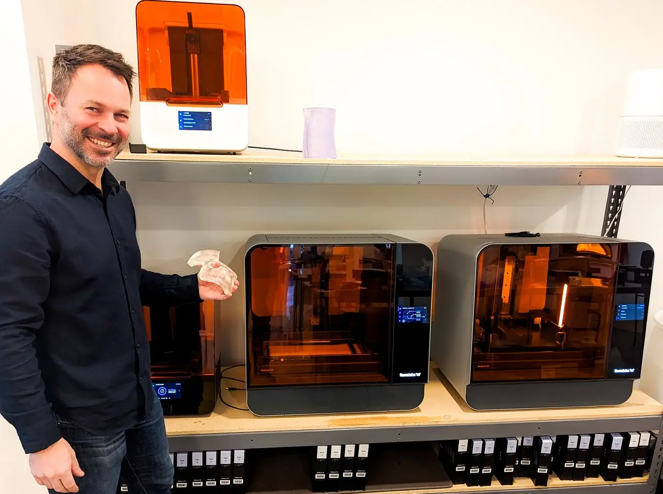 Man holding 3D printed bolus device standing next to Form 3 series 3D printers