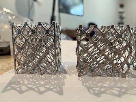 Two copies of a 3D printed lattice structure. The left one is intact and the right one has been flattened by approximately 5-10% in a compression test.
