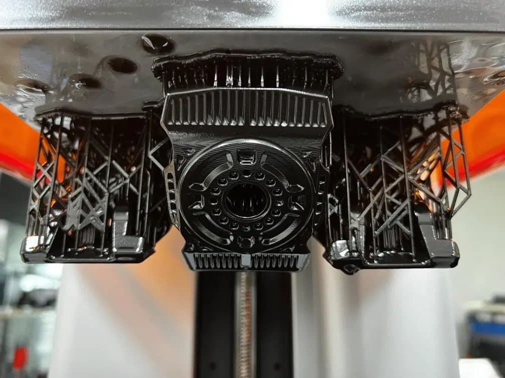 Black 3D printed parts on supports still on the Build Platform in Form 4