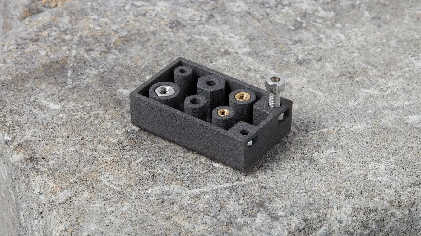 Pièce de test avec une vis mécanique installée dans un écrou inséré dans une poche sur le côté de la pièce.