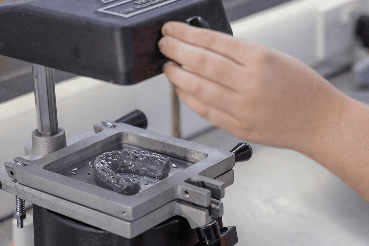 Ein Techniker bei Ashford Orthodontics nutzt einen Vakuumformautomaten zur Herstellung transparenter Aligner.