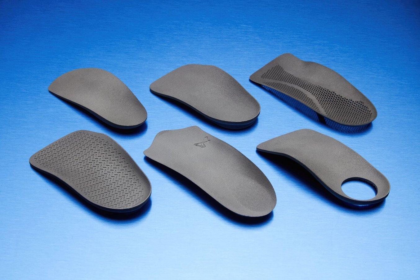 Six 3D printed insoles on a blue background