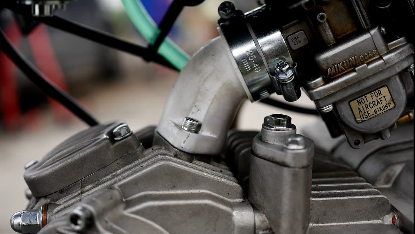 Close-up on the air intake area of an engine, with a dirty white 3D printed part installed.