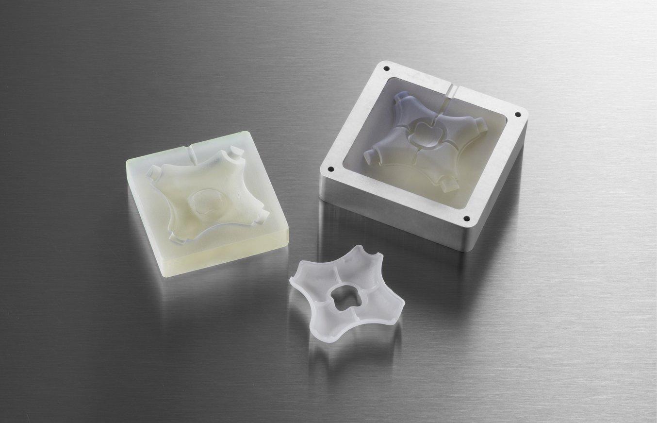 Moldes de inyección impresos en 3D en un marco de aluminio y la pieza moldeada por inyección acabada.