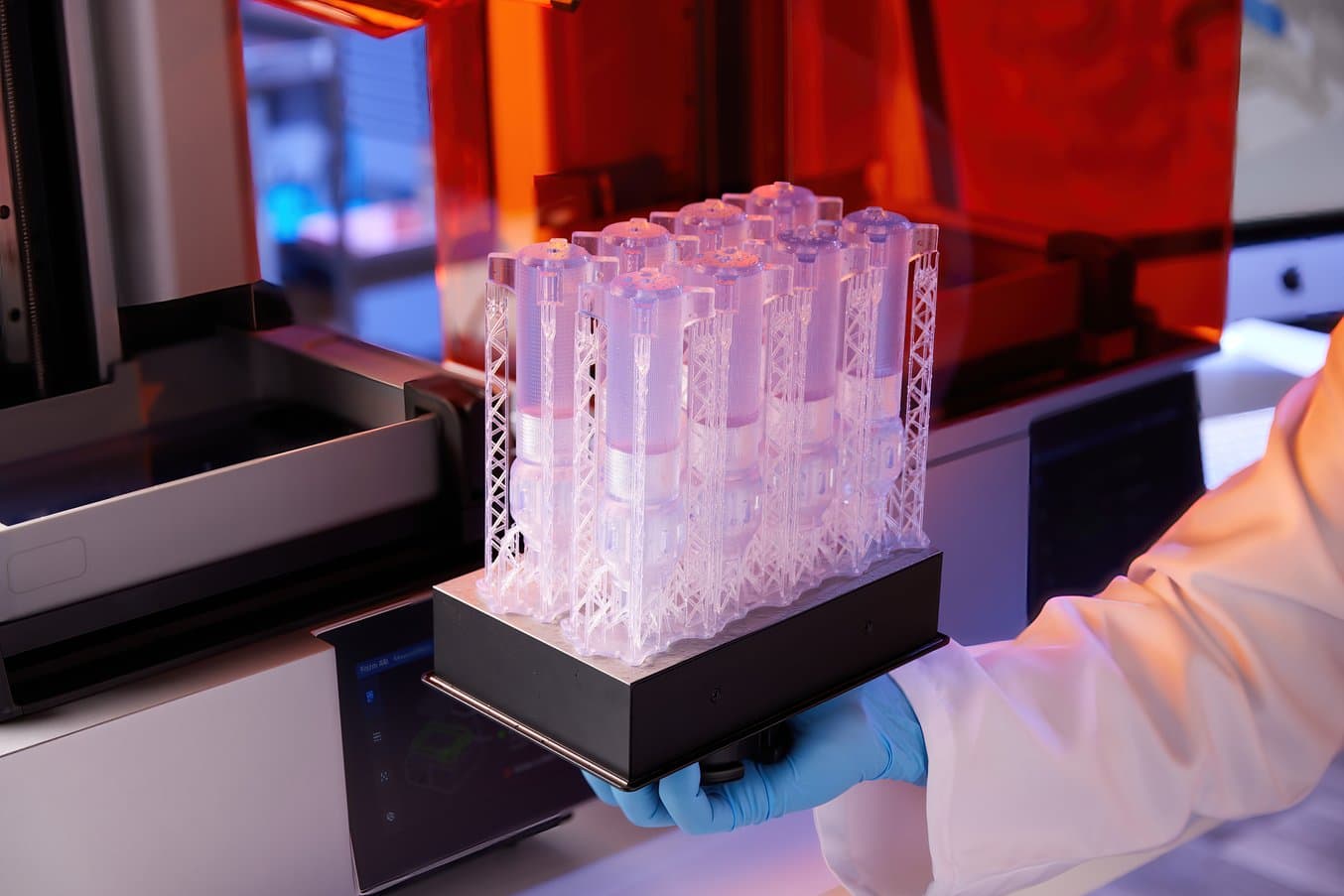 Clear, 3D printed medical devices on build platform in front of Form 4B 3D printer