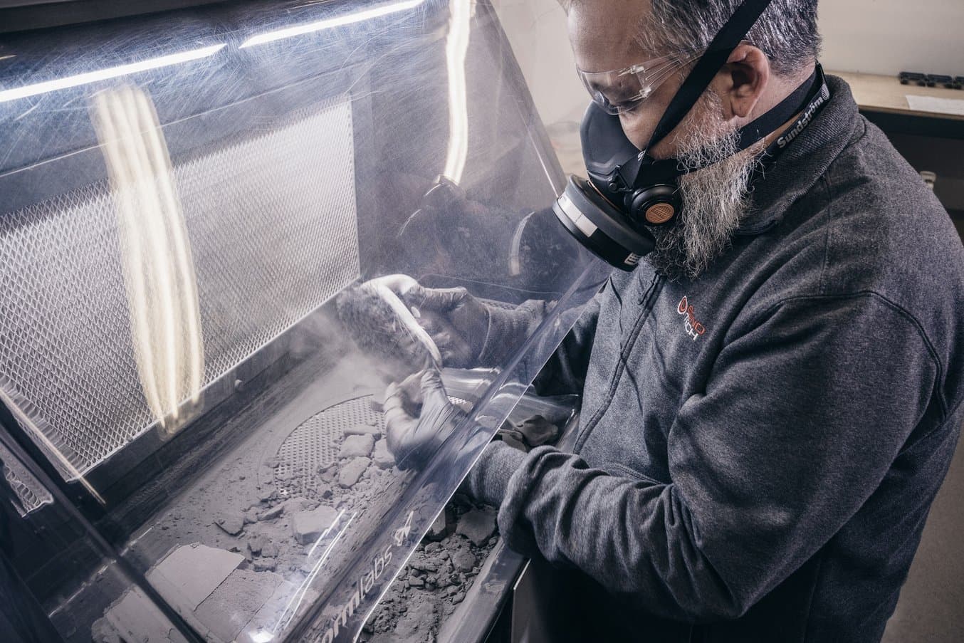 A man removes powder from a 3D printed part in the Formlabs Fuse Sift