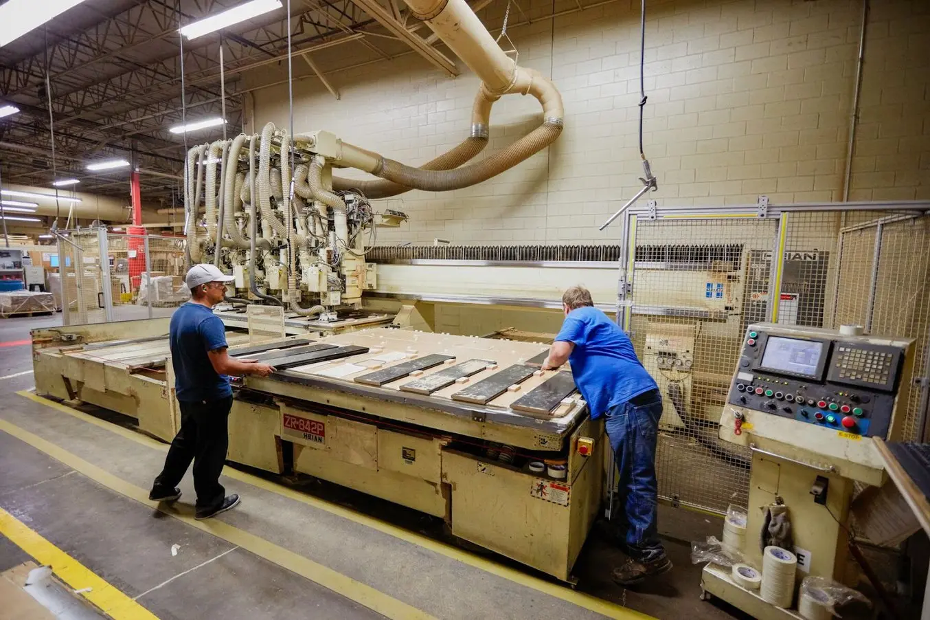 Two people in blue shirts work at the Ashley Furniture factory
