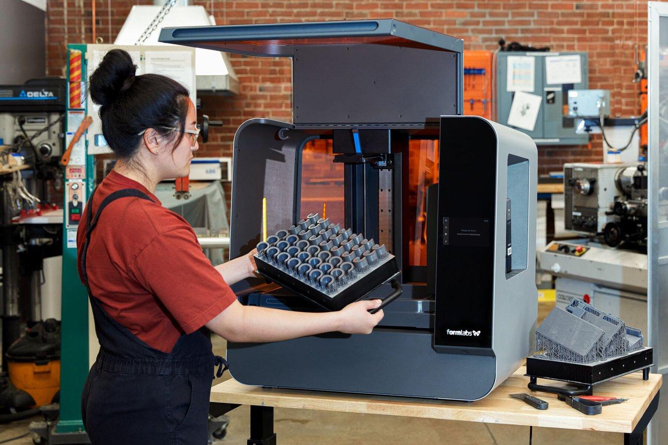 woman taking out a build platform from a Form 3L stereolithography printer