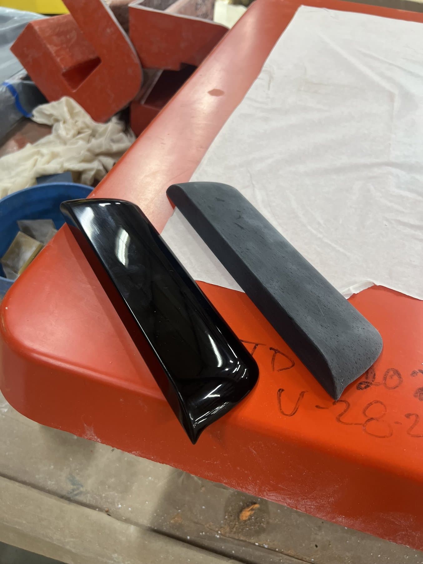 Two black parts on a red background. The left part is a glossy black and the right is grayer and matte.