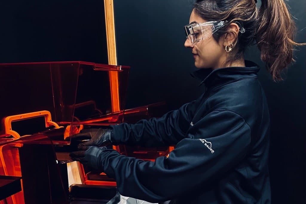 Woman wearing eye protection and gloves removing a print from a printer