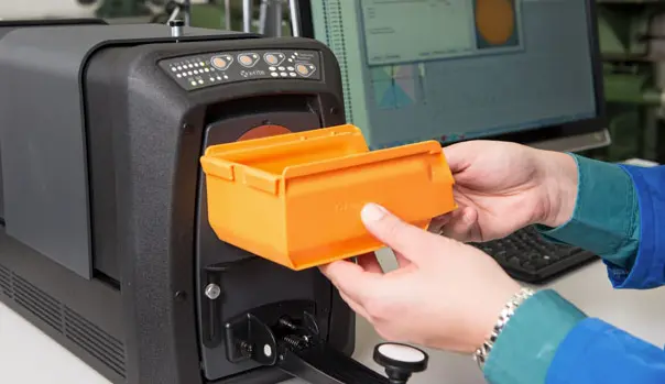 person holding an orange part up to a spectrophotometer
