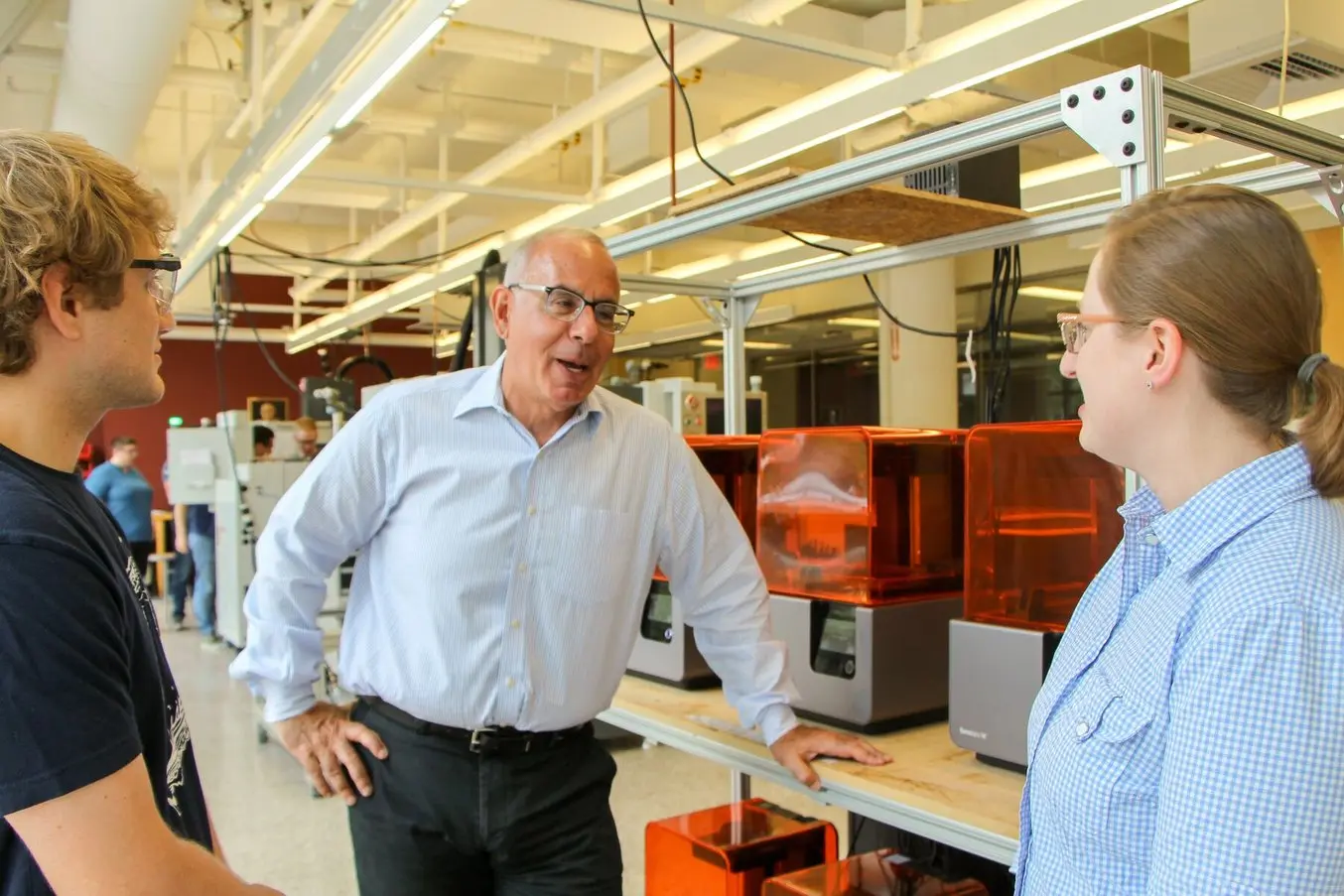 Un professeur s'adresse à deux étudiants dans une installation de fabrication additive