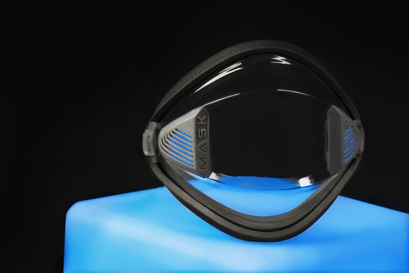 La G-Mask appoggiata su un piedistallo di colore blu e una parete nera sullo sfondo.