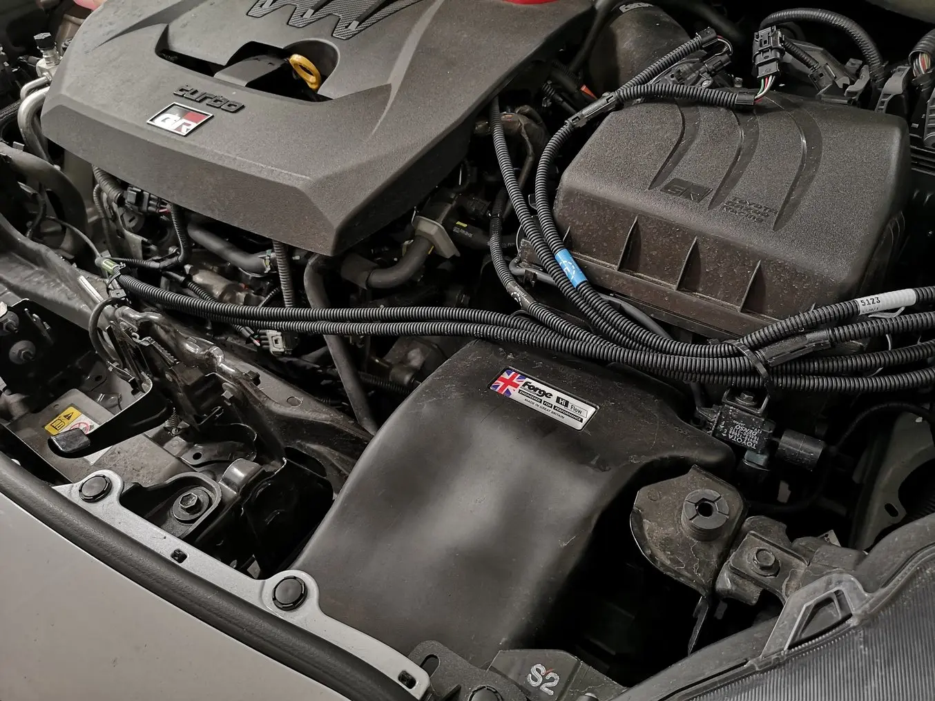 Under the hood of a car, a 3D printed inlet duct has been painted black.