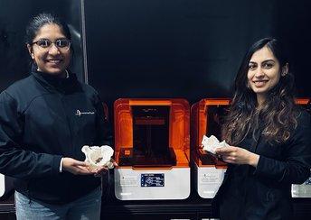 Two women stand in front of Form 3B+ 3D printers holding surgical models
