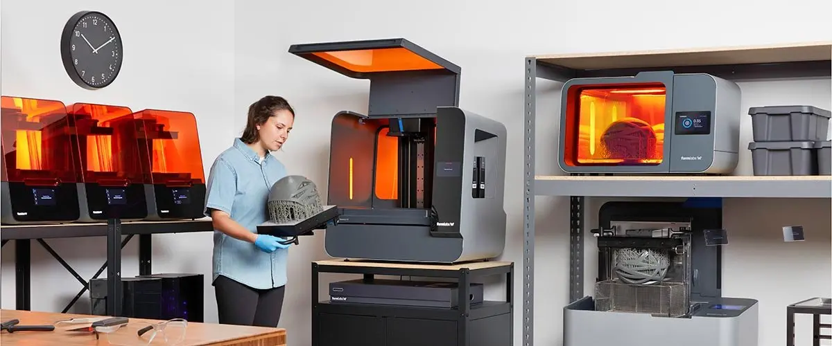 a woman stands in front of a large format SLA 3D printer