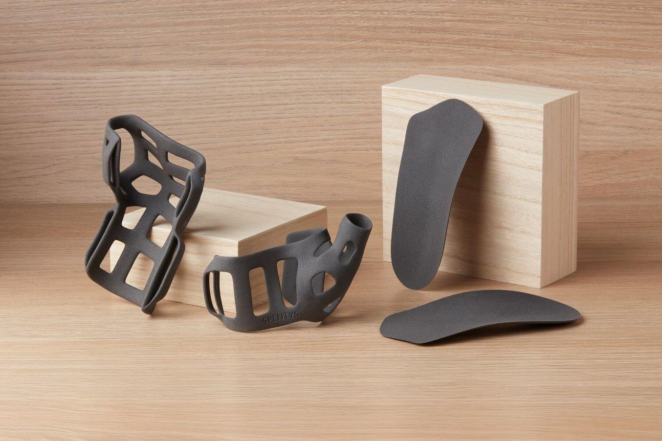 polypropylene powder sls 3d printed medical devices on a wooden background, a 3d printed thumb brace and orthoses