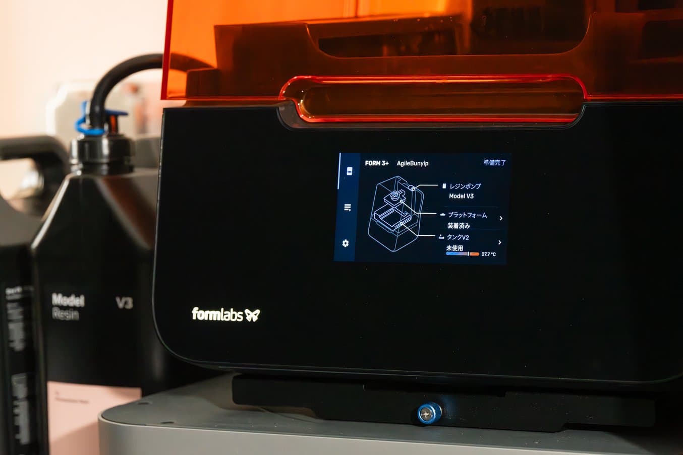 Close up on the front of a Form 3+ 3D printer screen. A 5 L resin container is visible in the background.