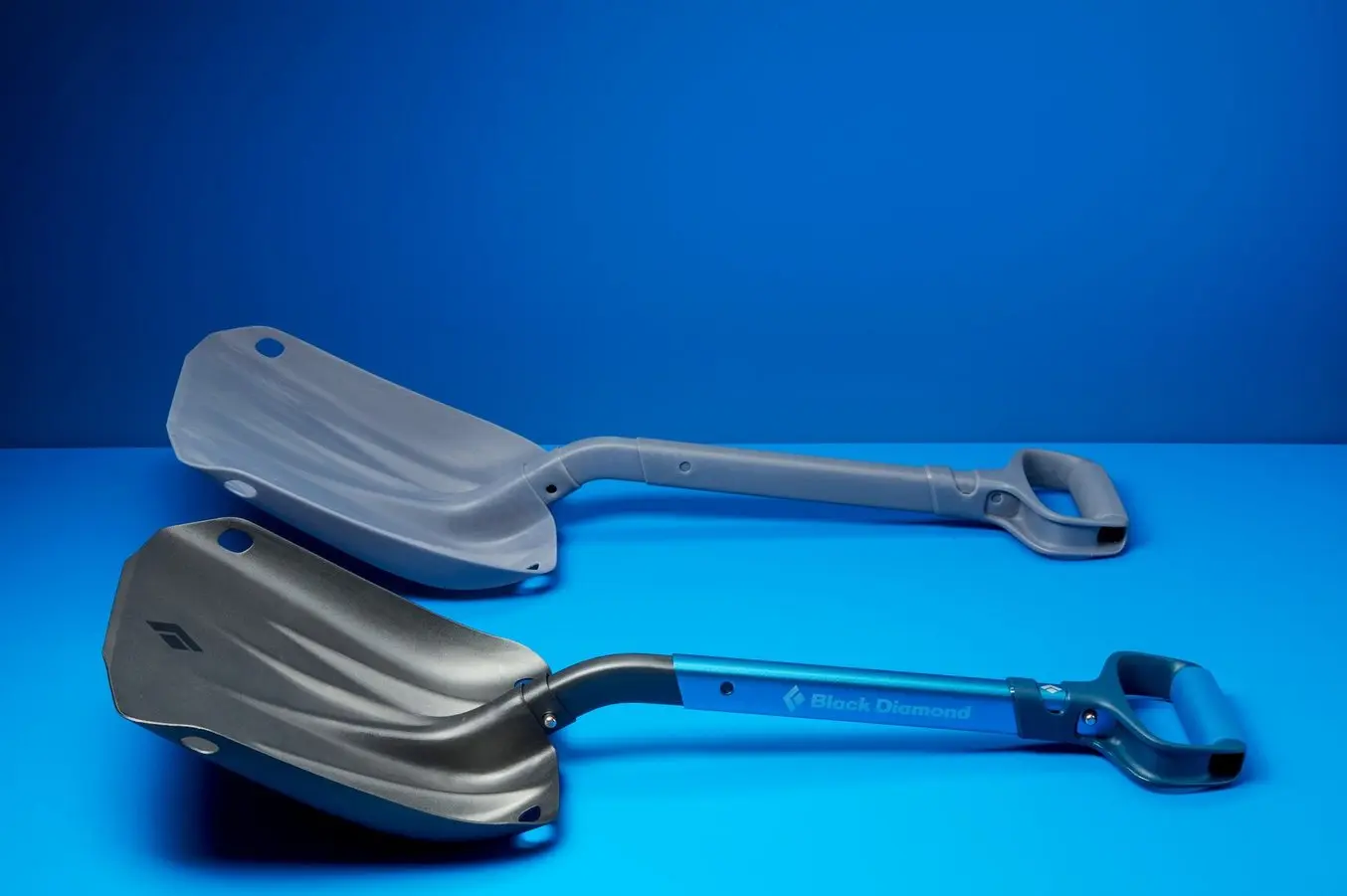 a prototype of a Black Diamond shovel on a blue background next to the real end-use manufactured shovel